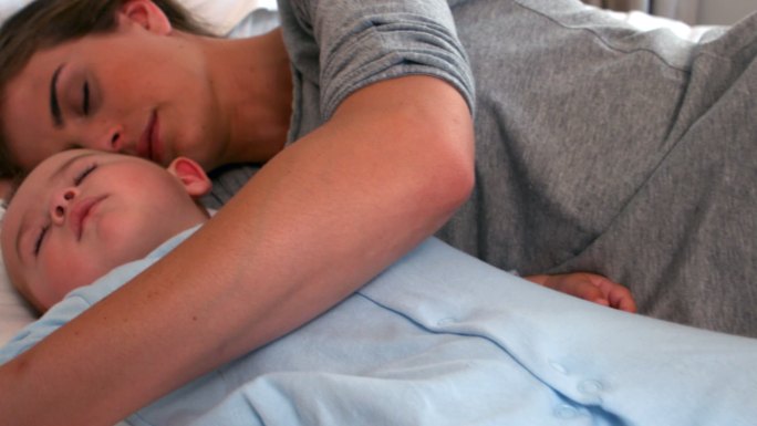 慢镜头里，小男孩和妈妈一起睡在床上