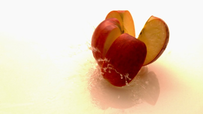 苹果在白色潮湿的表面缓慢下落和弹跳