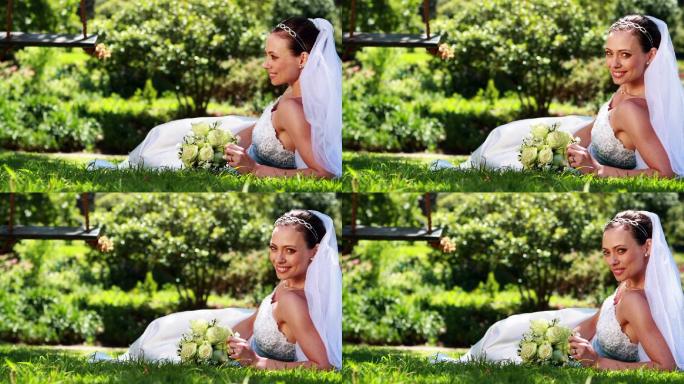 美丽的新娘在她的婚礼上对着镜头微笑躺在草地上