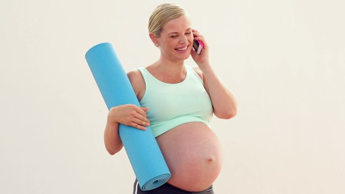 怀孕的金发美女在健身房里打电话