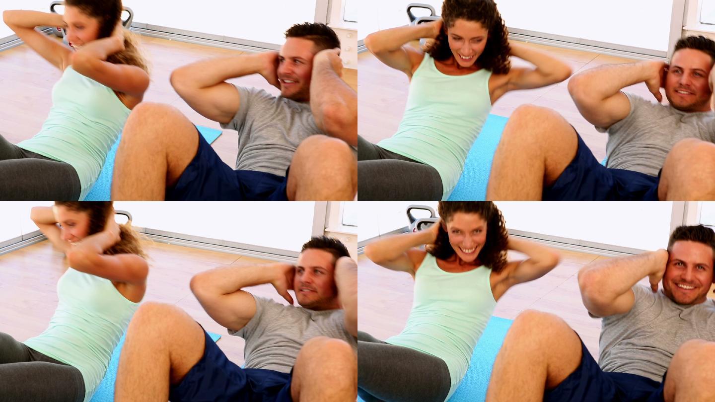 一对幸福的情侣在健身房一起做仰卧起坐