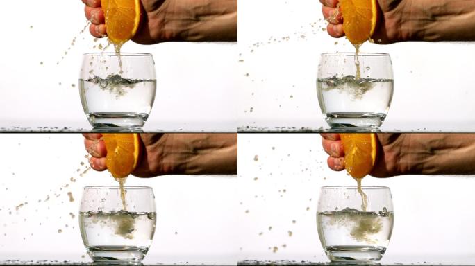 用手把橙汁慢动作挤进一杯水里