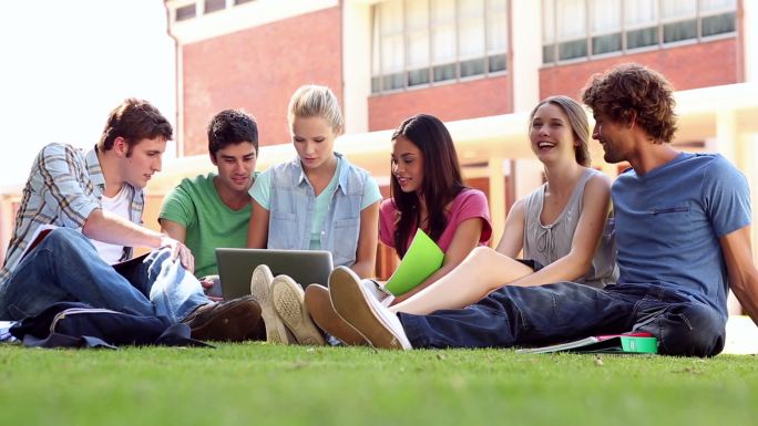 同学们坐在大学里的草地上聊天