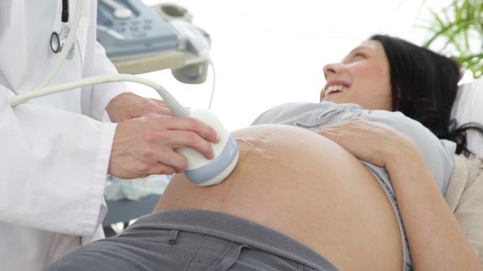 一个深褐色的孕妇正在医院的办公室里做超声波扫描