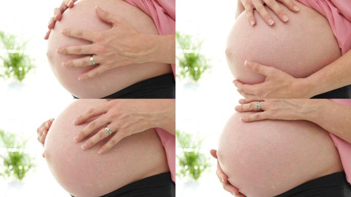 一名孕妇在医院办公室摸着自己的肚子