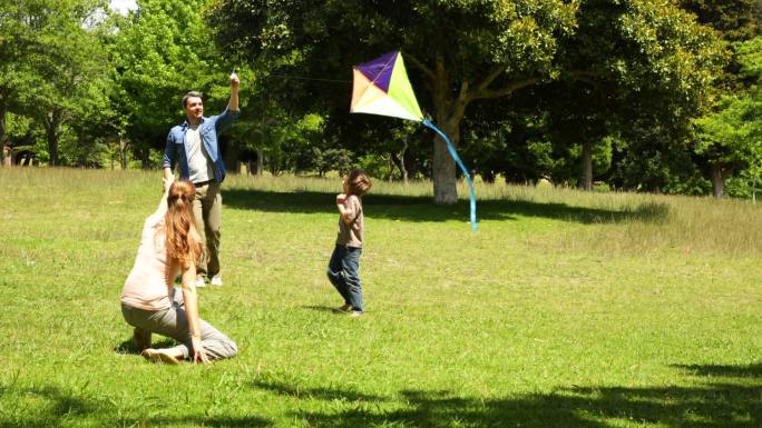 一个阳光明媚的日子，小男孩和父母在公园里放风筝