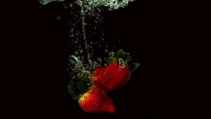 草莓落在水中的黑色背景慢动作