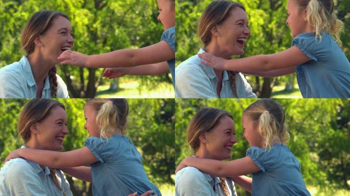 年轻的母亲在公园里用慢镜头拥抱她的女儿