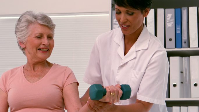 理疗师以慢动作帮助病人举起重物