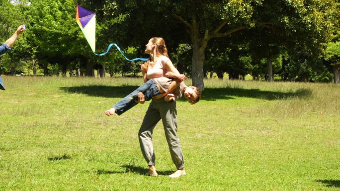 在一个阳光明媚的日子里，小男孩和父母在公园里放风筝嬉戏