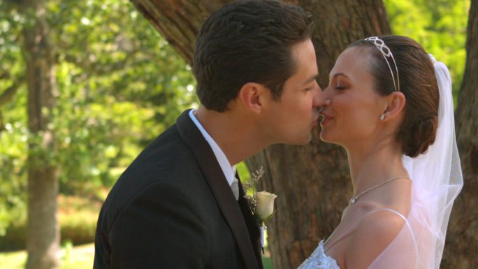 一对新婚夫妇在公园里接吻的慢镜头