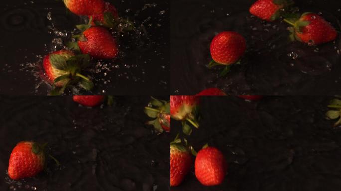 草莓以慢动作落在潮湿的黑色表面上