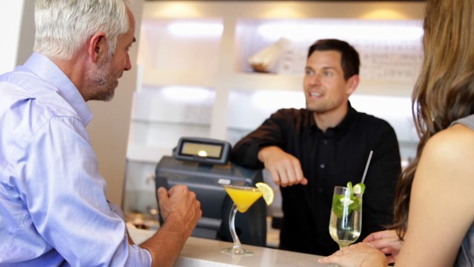 调酒师在当地酒吧提供鸡尾酒和与顾客聊天