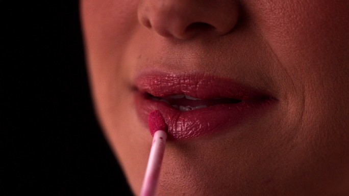 一个女人在慢镜头里涂着粉色的唇彩