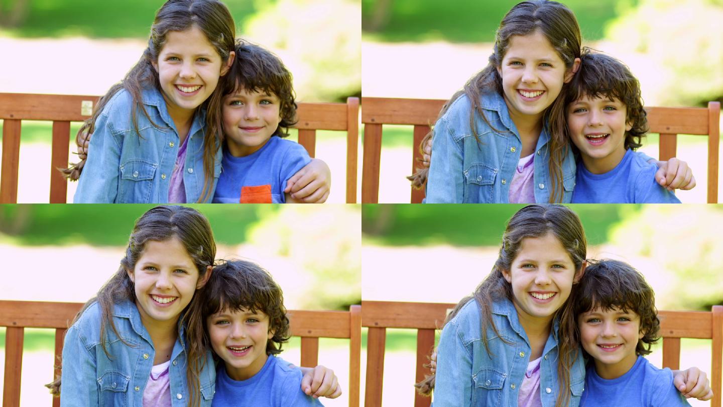 在一个阳光明媚的日子里，哥哥和姐姐在公园的长椅上拥抱