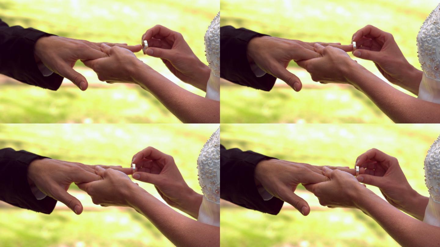 在慢镜头中，女子将戒指戴在新郎的手指上