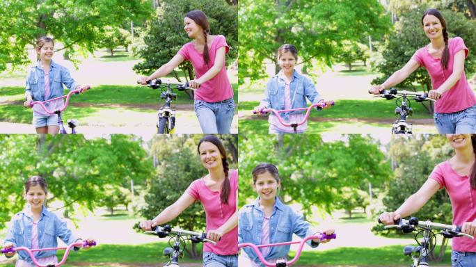 在一个阳光明媚的日子里，可爱的妈妈和女儿一起推着自行车在公园里