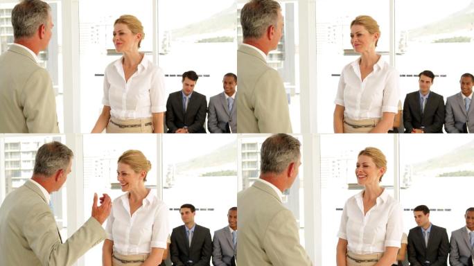 一个商人在办公室和一个求职者握手并和她交谈