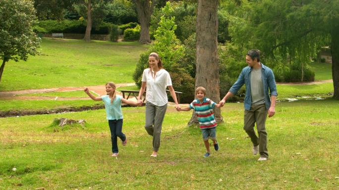 快乐的一家人在公园里蹦蹦跳跳的慢镜头