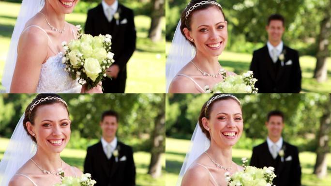 在一个阳光明媚的日子里，美丽的新娘对着镜头微笑，新郎站在后面