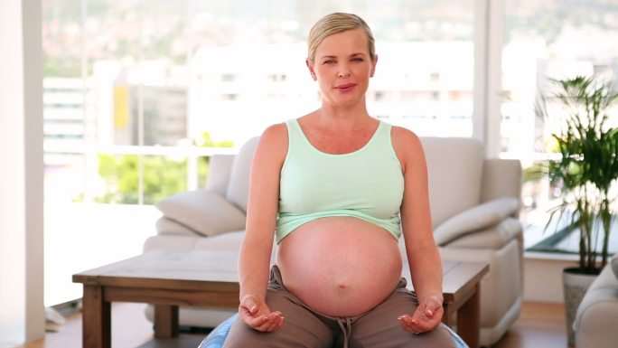 一个孕妇坐在健身球上移镜头