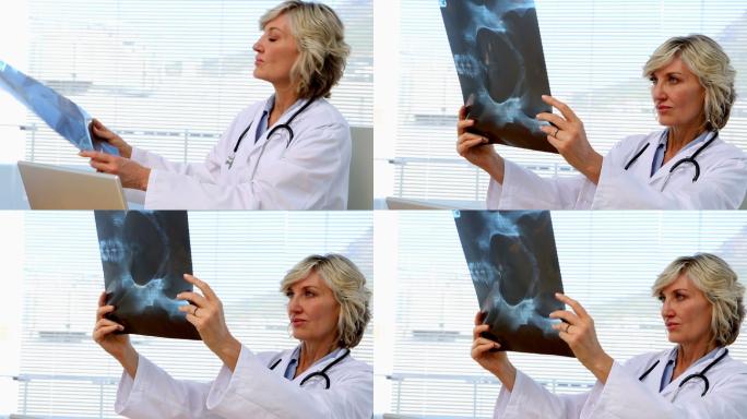 一位金发医生在医院办公室的办公桌前看x光片