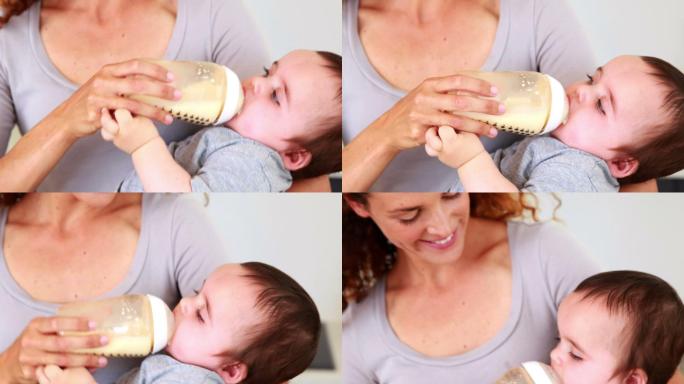 快乐的母亲在家里的厨房里给她的宝贝儿子喂奶