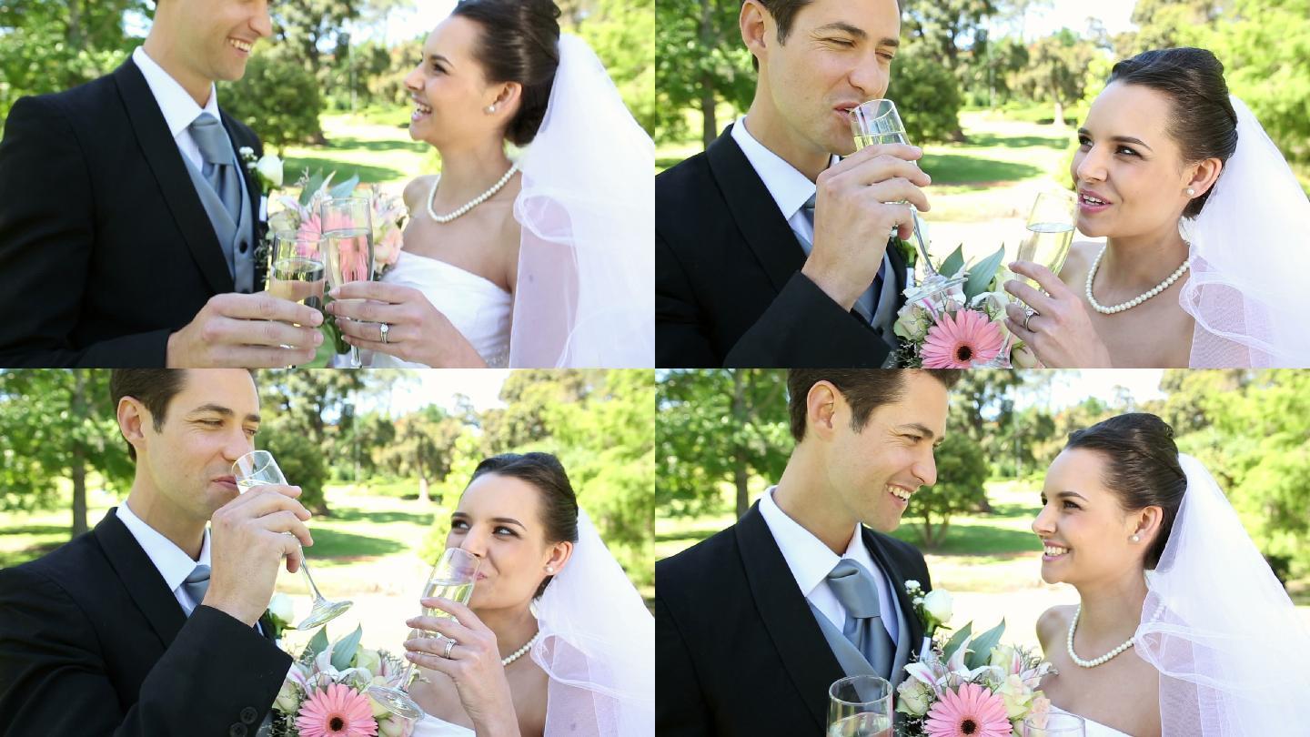 快乐的新婚夫妇在阳光明媚的日子用香槟在婚礼蛋糕旁敬酒