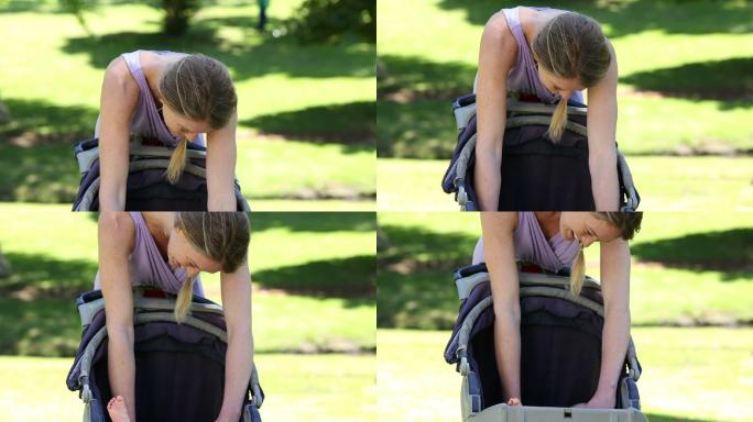 在一个阳光明媚的日子里，母亲在公园里推着婴儿车照顾她的小女儿