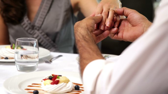 一个男人在餐馆里给新未婚夫戴上戒指