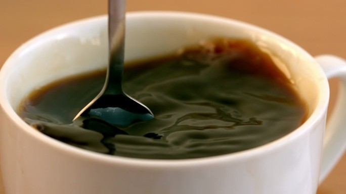 用茶匙在杯子里慢动作搅拌咖啡