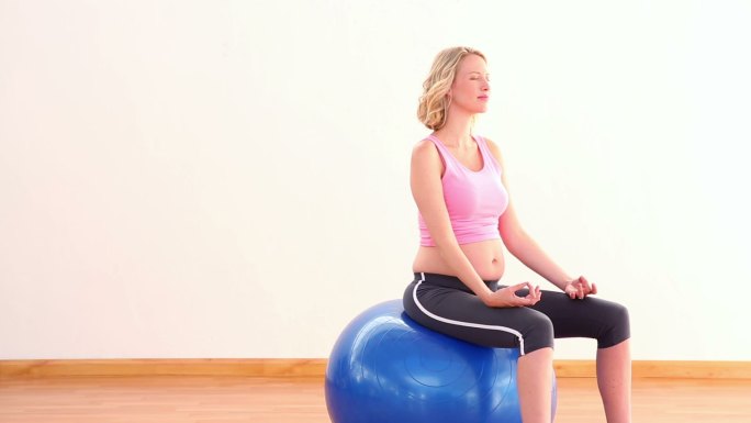 一个孕妇坐在健身球上移镜头