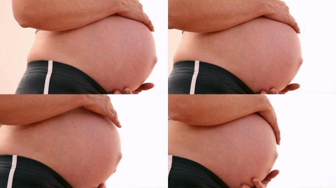 一个孕妇在健身房里抱着她的肚子
