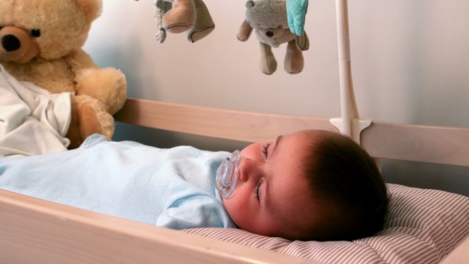 慢镜头里的小男孩睡在婴儿床里