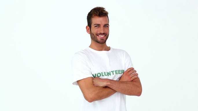 英俊的志愿者对着白色背景的相机微笑