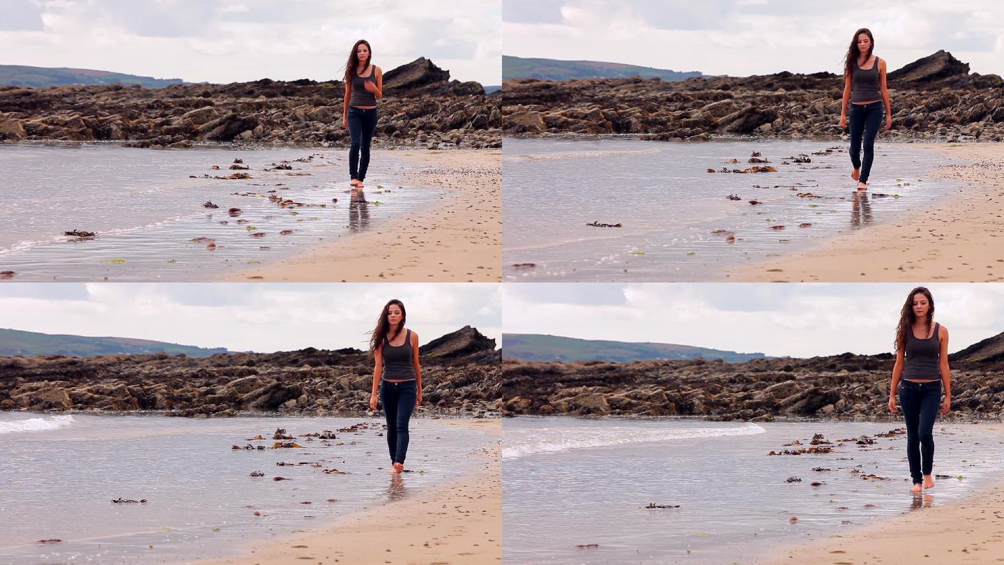 一个漂亮的黑发女人在阴天沿着海边散步