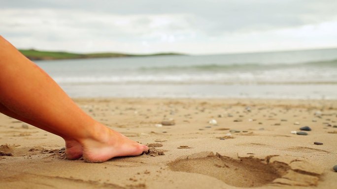 阴天坐在海滩上的女人的腿