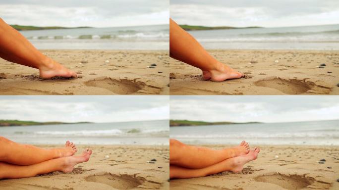 阴天坐在海滩上的女人的腿