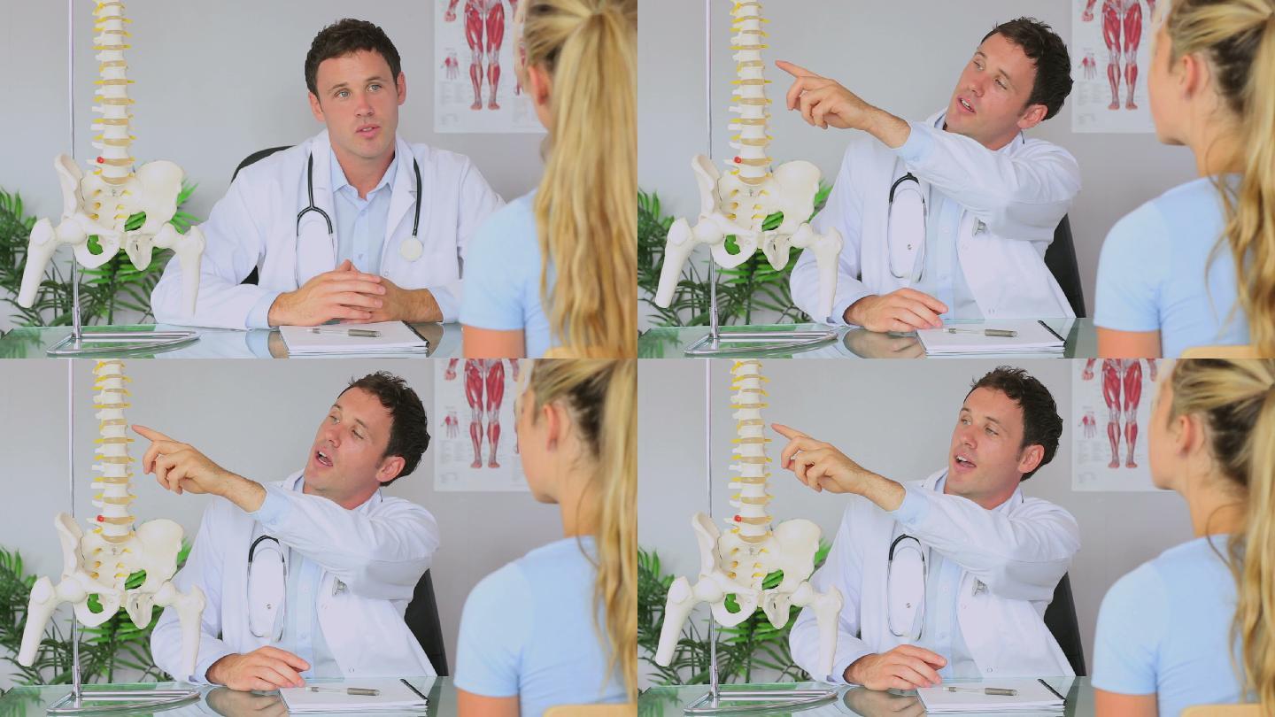 脊椎治疗师与他的病人交谈，并指着脊椎模型