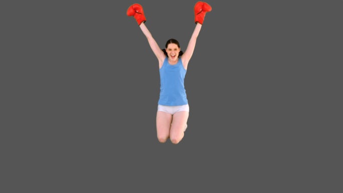女人穿着运动服戴着拳击手套跳跃特写