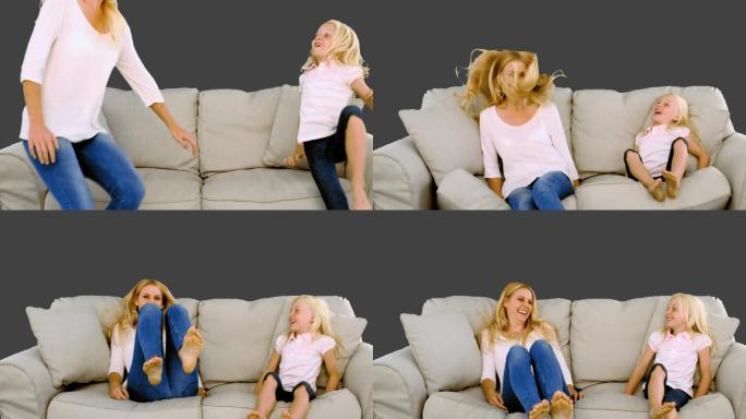 灰色背景下母亲和女儿跳到沙发上特写