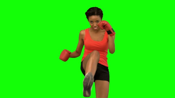 绿色屏幕下女人戴着拳击手套踢腿特写