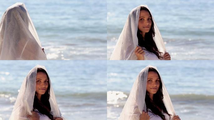 有魅力的女人看着大海，戴着围巾