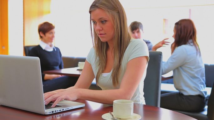 女生在大学食堂里看电脑学习特写
