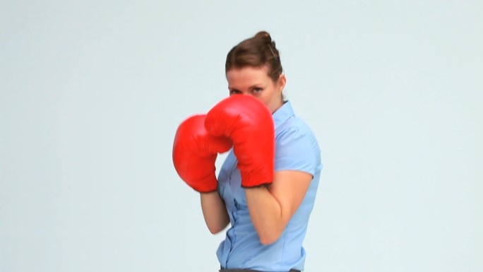 女人在白色背景下戴着拳击手套打拳特写