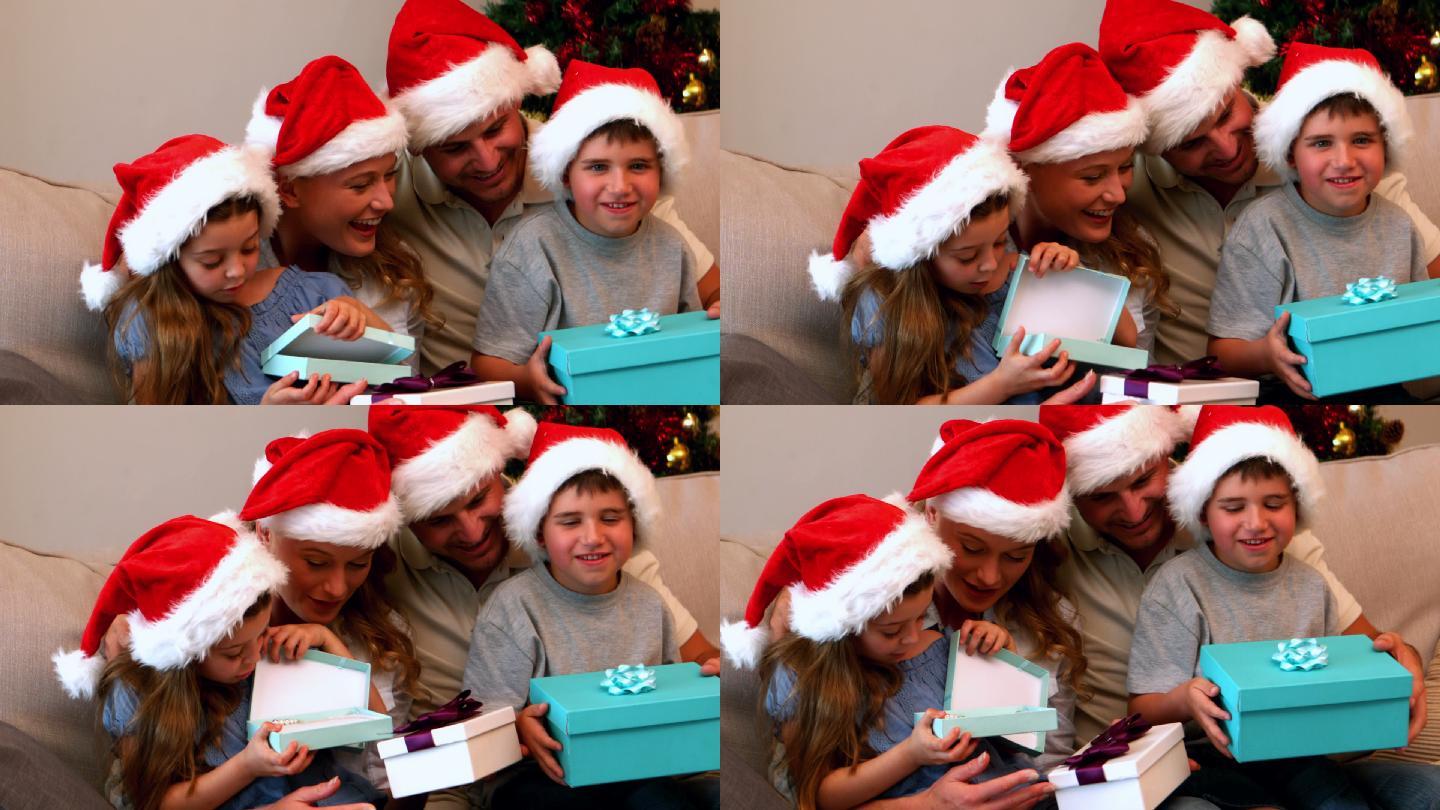 快乐的年轻家庭在沙发上慢镜头打开圣诞礼物