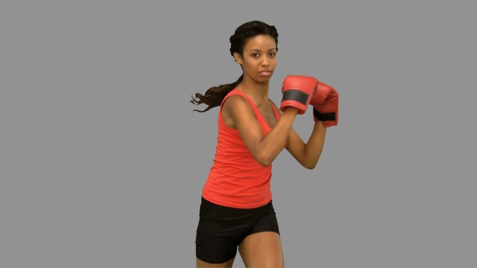 女人戴着拳击手套在灰色背景下打拳特写