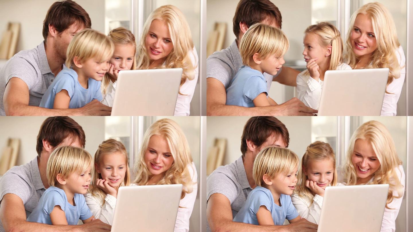 父母和孩子在用一台白色笔记本电脑聊天