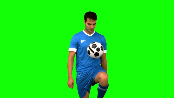 一个足球运动员在绿色背景下练习足球特写