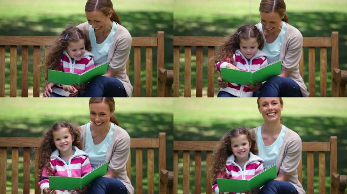 妈妈在公园的长椅上给女儿讲故事特写